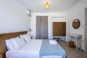 a bedroom with a bed with white sheets and a mirror at Naxos Infinity Villa and Suites in Naxos Chora +53 photos
