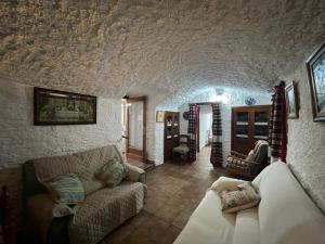 a living room with a couch in a stone wall at Las cuevas de María in Bácor
