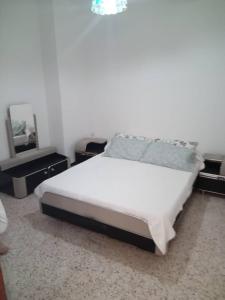 a bedroom with a white bed and a mirror at Résidence EPLF SAKET BÉJAÏA in Bejaïa