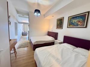 a bedroom with two beds and a desk and a chandelier at Apartments Lungo Mare in Sveti Stefan