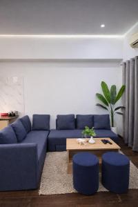 a living room with a blue couch and blue stools at Glory Stays in Noida