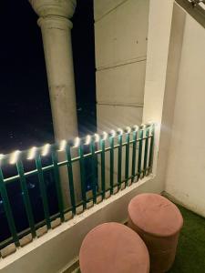 a balcony with two stools and a railing with lights at Glory Stays in Noida