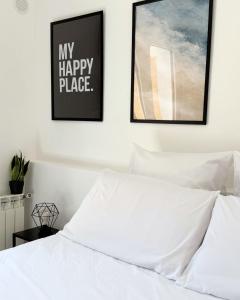 a bedroom with a white bed with two framed pictures on the wall at Maya Apartments in La Maddalena