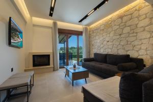 a living room with a couch and a stone wall at Afitos Luxury Villas in Afitos