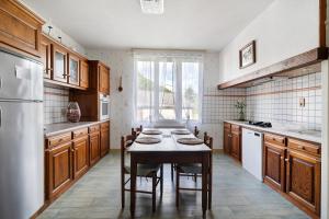 a kitchen with a table with chairs and a refrigerator at Maison de vacances La Couade in Troche