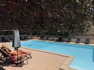 a woman laying in a chair next to a swimming pool at Hôtel Restaurant L' Empereur in Aléria