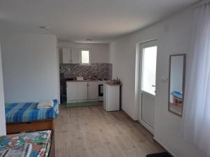 a small room with a kitchen and a bed and a mirror at Perucac Apartman in Perućac