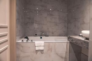 a white bathroom with a tub and a sink at Boutique Hotel De Doelen in Groningen