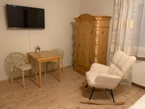 a living room with a table and a chair and a television at Ferienwohnung "Zirbenduft" im Landhotel Seeg in Seeg