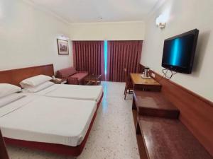 a hotel room with a bed and a flat screen tv at Trance Oakwood Hotel in Pune