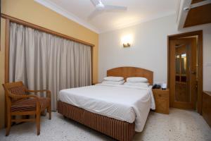 a bedroom with a large bed and a chair at Trance Oakwood Hotel in Pune +4 photos
