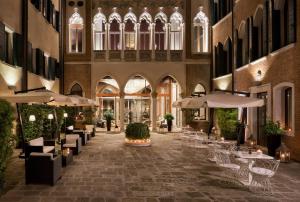 ein Innenhof mit Tischen und Sonnenschirmen in einem Gebäude in der Unterkunft Sina Centurion Palace in Venedig