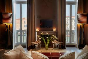 ein Wohnzimmer mit Sofa, Fernseher und Fenstern in der Unterkunft Sina Centurion Palace in Venedig