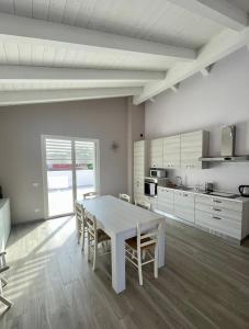 a white kitchen with a white table and chairs at Villa Giovanna Rooms in Montelabbate