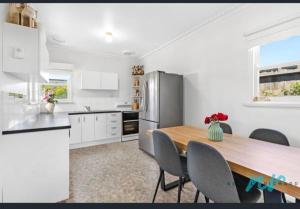 a kitchen with a wooden table and a refrigerator at Timber and Tide in Saint Leonards