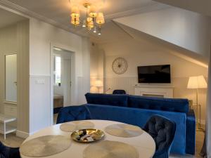 a living room with a blue couch and a table at Rezydencja De Rosse in Jastrzębia Góra