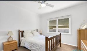 a bedroom with a bed with a ceiling fan and a window at Timber and Tide in Saint Leonards