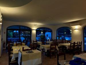 a dining room with tables and chairs and windows at Residenz e Ristorante da Mimì in Forio d'Ischia