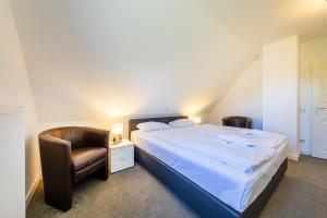 a bedroom with a large bed and a chair at Haus Sonnenschein 2 in Ahrenshoop
