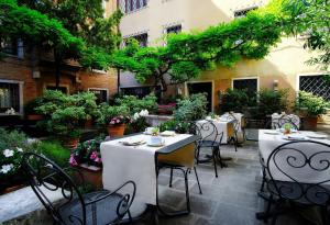 a restaurant with white tables and chairs and trees at Sina Palazzo Sant'Angelo in Venice