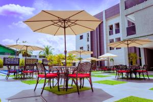a group of tables and chairs with umbrellas at Grande Candor Exclusive Hotel in Warri Airport
