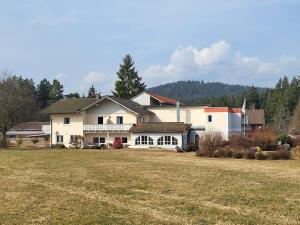 a large white house with a field in front of it at Landhaus Auhirsch in Böbrach