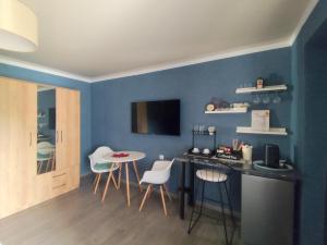 a room with a blue wall with a table and chairs at Haus Georg in Zugdidi