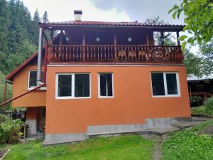 a house with a balcony on top of it at Paradisul Verde din Apuseni in Lăzeşti