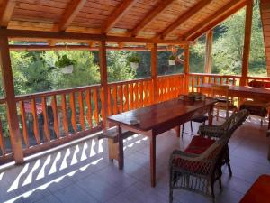 a screened in porch with a wooden table and chairs at Paradisul Verde din Apuseni in Lăzeşti