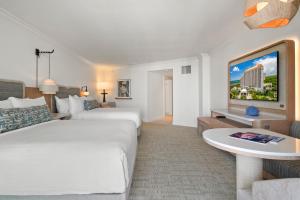 a hotel room with two beds and a flat screen tv at Naples Grande Beach Resort in Naples +30 photos