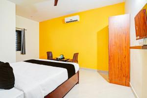 a bedroom with a bed and a yellow wall at Hotel O JK Blue Rock Comforts in Bangalore