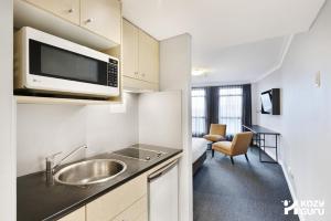 a kitchen with a sink and a microwave at KozyGuru | Sydney CBD | Best Location Studio in Sydney