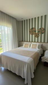 a bedroom with a large white bed and a window at AMARE Condomínio ap 103 in Barra Grande +13 photos