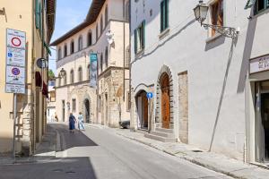 a woman walking down a street in an alley at Ser Lapo - Dimora storica a Prato in Prato