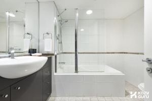 a white bathroom with a sink and a shower at KozyGuru | Sydney CBD | Best Location Studio in Sydney +22 photos