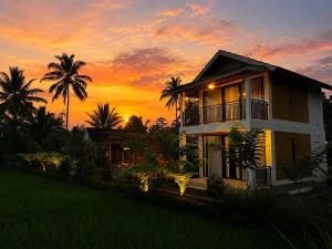 a house with a sunset in the background at PANORAMA BUNGALOWs in Tetebatu