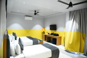 two beds in a room with yellow and white at Chitra's City Side Resort in Solapur