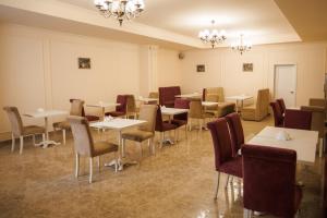 a dining room with tables and chairs and chandeliers at City Center Residence in Chernivtsi
