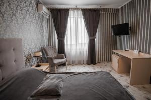 a hotel room with a bed and a desk and a television at City Center Residence in Chernivtsi +45 photos