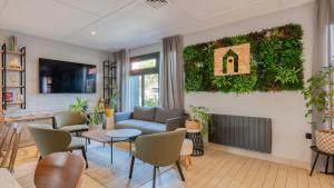 a living room with a couch and a living wall at Campanile NATURE - Brive-la-Gaillarde in Brive-la-Gaillarde