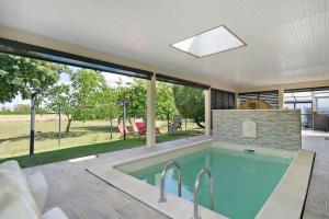 a swimming pool in a house with a large window at La Casa Andréa in Villars-en-Pons