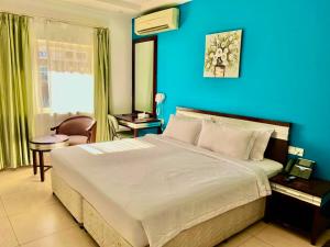 a bedroom with a large bed with a blue wall at Saffron Hotel and Lounges in Muscat