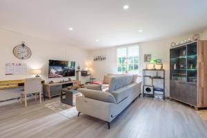 a living room with a couch and a tv at La Jardinette - Avec jacuzzi privé in Futeau