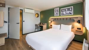 a bedroom with a large white bed and a green wall at Campanile NATURE - Brive-la-Gaillarde in Brive-la-Gaillarde