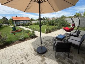 a patio with an umbrella and chairs and a table at Къща Грийн Хаус in Chernomorets