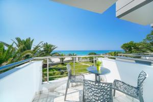 a balcony with a table and chairs and the ocean at OzioMari Suites in Limenaria
