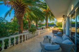 ein Balkon mit Stühlen, einem Tisch und Palmen in der Unterkunft B&B Sidro in Vodice