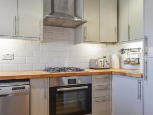 a kitchen with white cabinets and a stove top oven at Coed Faen in Saint Helens