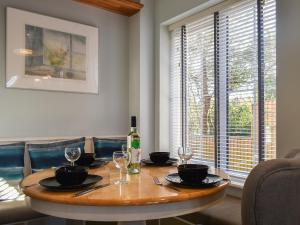 a dining room table with a bottle of wine and glasses at Coed Faen in Saint Helens