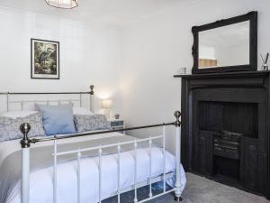 a bedroom with a bed with a mirror and a fireplace at Causeway Cottage in Wolsingham